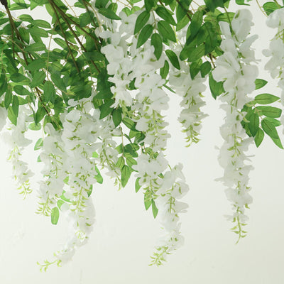 White floral garland with green leaves on a plain background