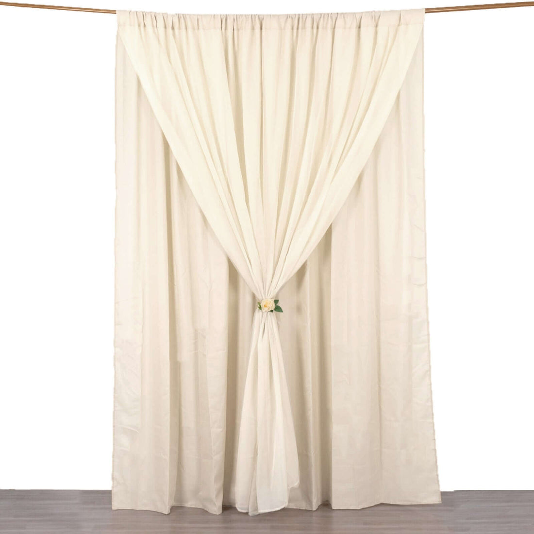 Cream curtain draped elegantly with a floral tieback on a white backdrop