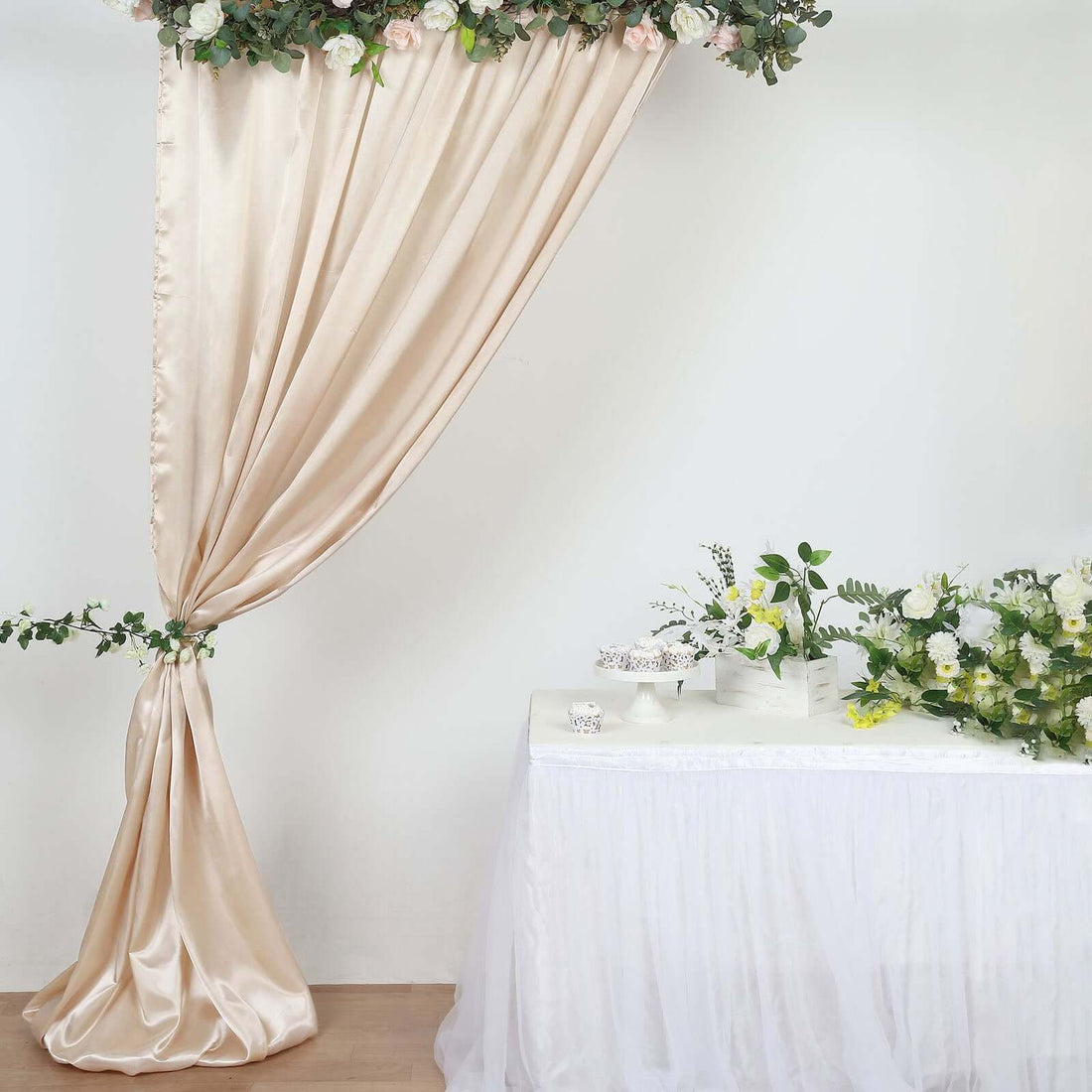 Elegant silk curtain draped with flowers beside a decorated table.