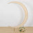 Moon-shaped backdrop with soft fabric and floral arrangements.