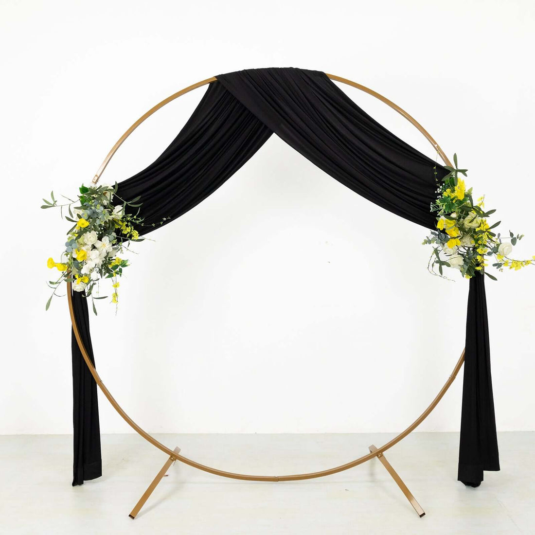 Gold circular wedding arch with black drapery and floral accents