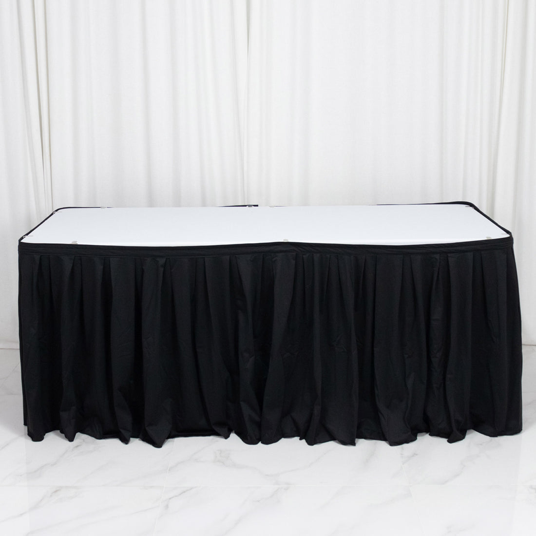 Black banquet table skirt with white tabletop on a draped backdrop