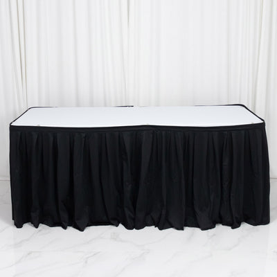 Black banquet table skirt with white tabletop on a draped backdrop