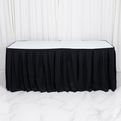 Black banquet table with white top and black pleated table skirt on white backdrop