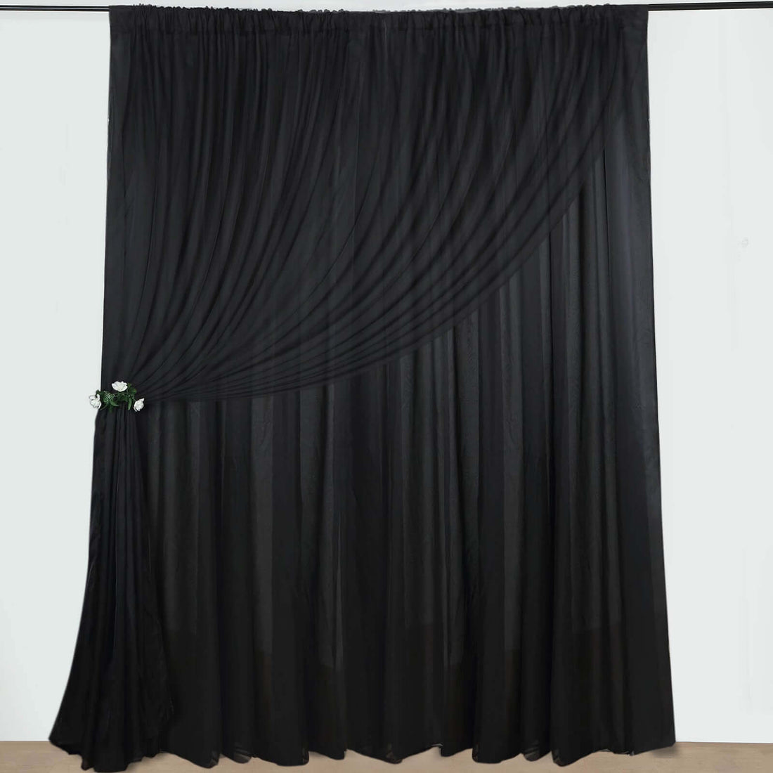 Black sheer curtain with draped design and floral accent.