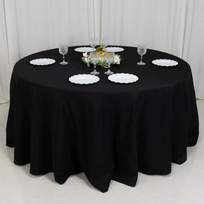 Round black table set with plates and glasses for an elegant dining experience.