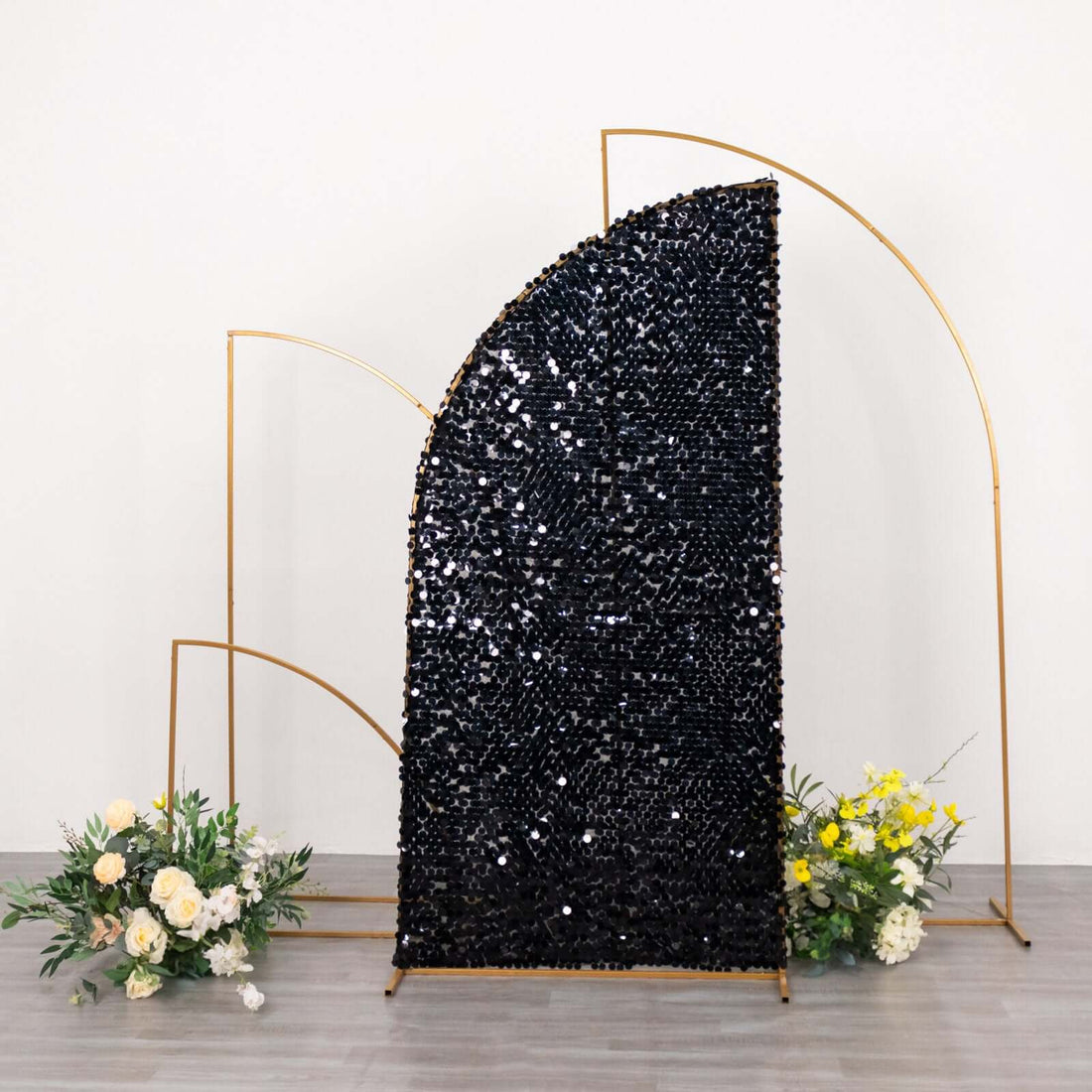 Decorative black sequined backdrop with gold frame and floral arrangements.