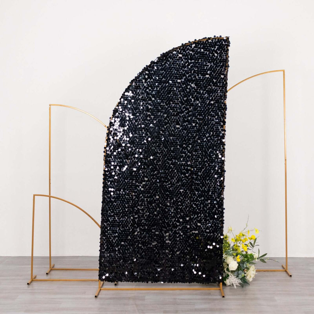 Black sequin backdrop with gold frame and floral arrangement at the base