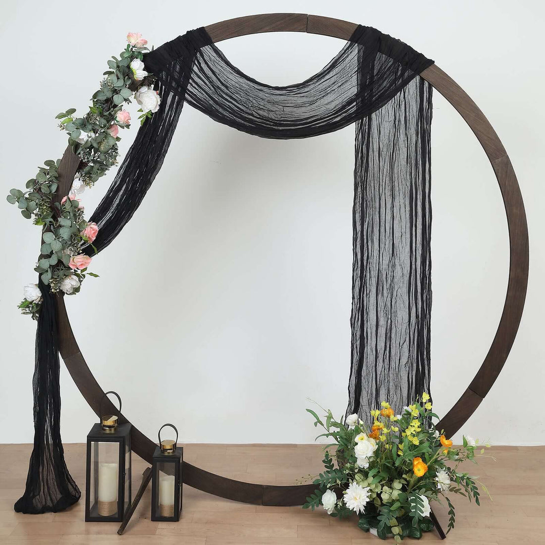 Decorative floral arch with drapes and lanterns for events or photography.