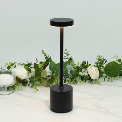 Black modern cordless table lamp with floral centerpiece on marble surface