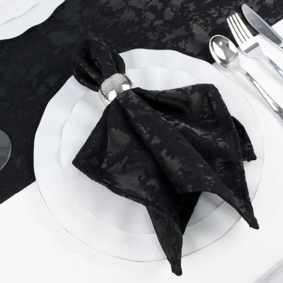 Black napkin folded on white dinner plate with silver cutlery, elegant table setting