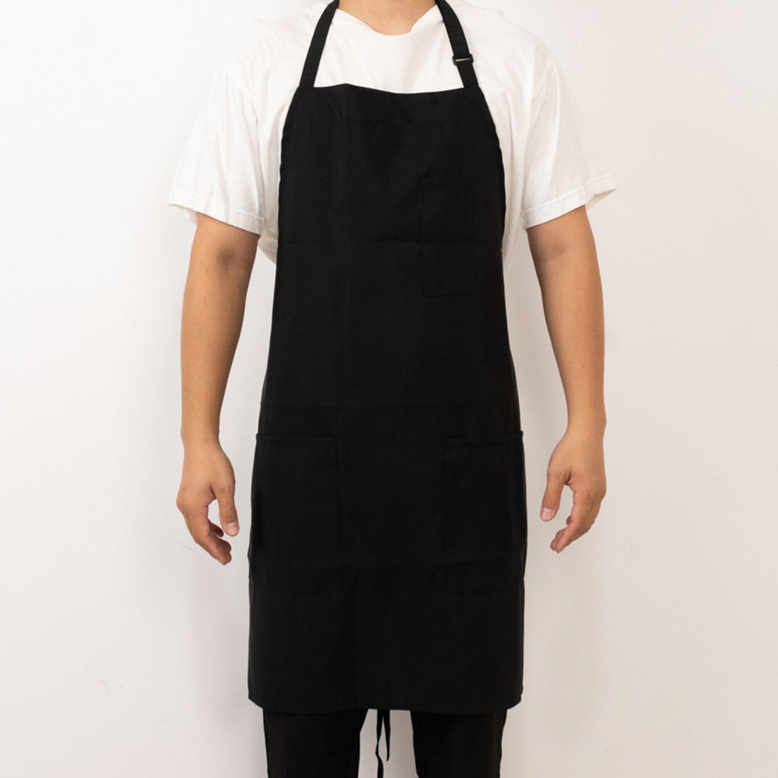 Black apron worn by a person, featuring pockets and adjustable straps.