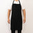 Black apron worn by a person, featuring pockets and adjustable straps.