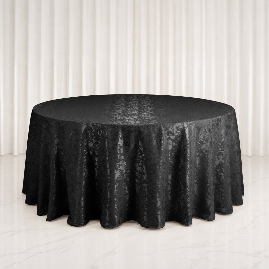 Black round satin tablecloth on banquet table with elegant draped backdrop