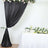 Black drapery with floral decor beside a decorated table of flowers.