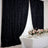 Black textured curtains draping a bright dining setup with floral centerpieces.