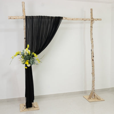 Black drapery backdrop with floral arrangement on a rustic wooden frame.