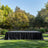 Outdoor event stage with black draped table in a lush garden setting.