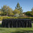 Outdoor black table skirt in a garden setting with lush greenery.