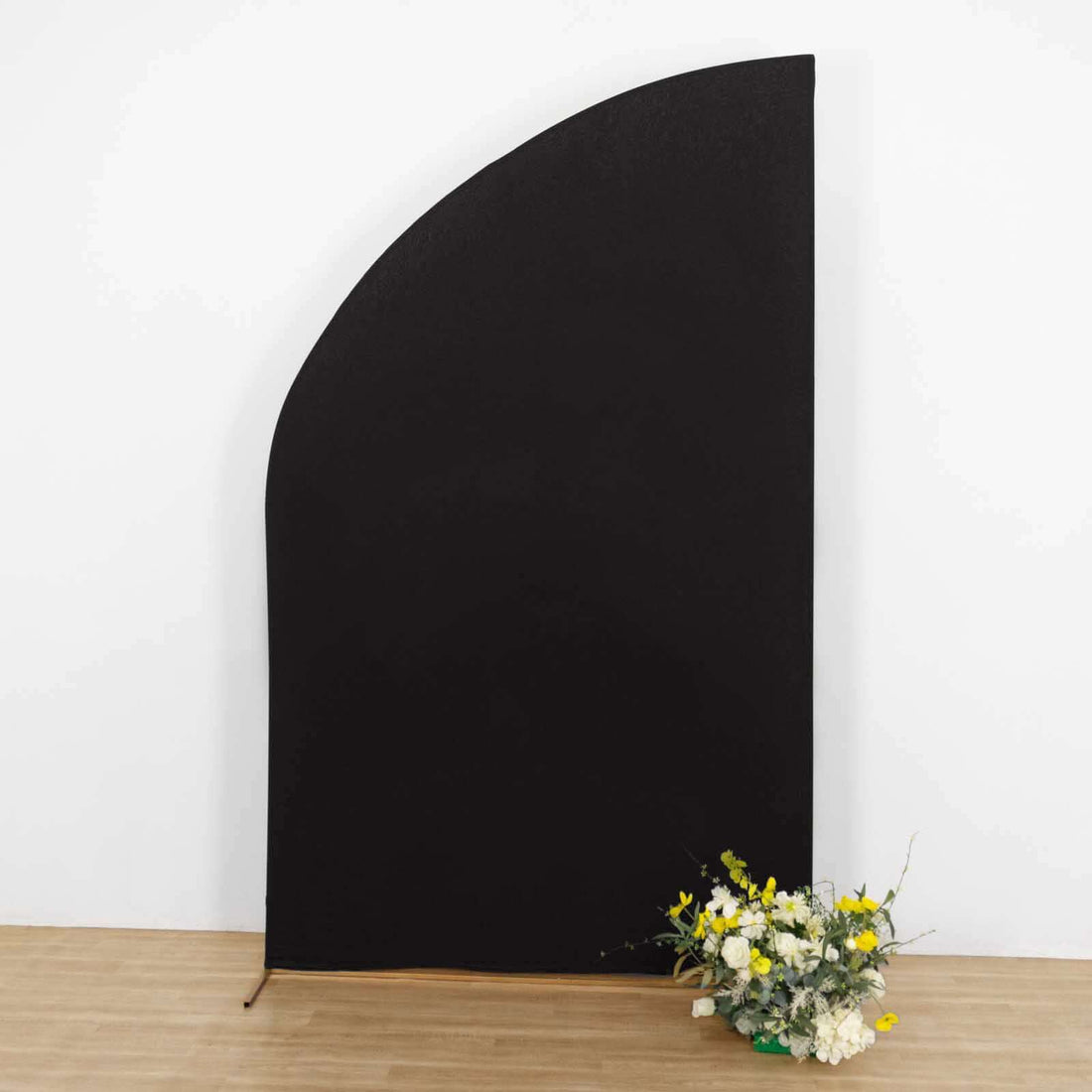 Black curved backdrop with artificial flowers on the floor.