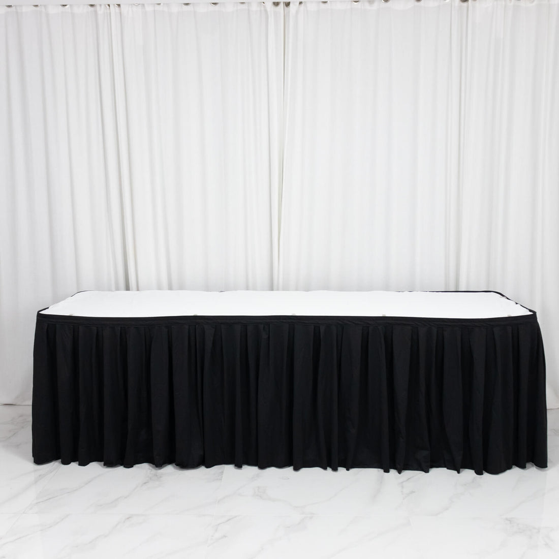 Black table skirt with white tabletop in elegant event setup, on white backdrop
