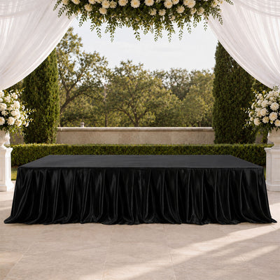 Black tablecloth on elegant outdoor wedding reception table with floral arch