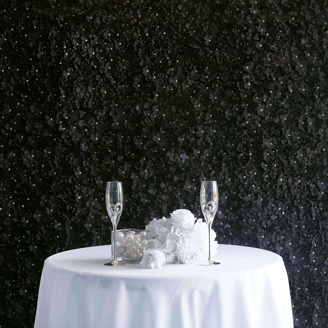 Elegant table setting with champagne glasses and white roses against a dark backdrop.