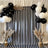 Black and white striped backdrop with balloons and decorative plants.