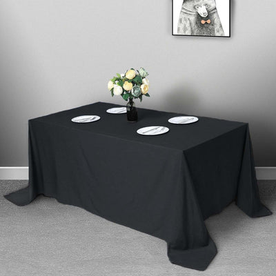 Black tablecloth draping over a table set with plates and flowers.