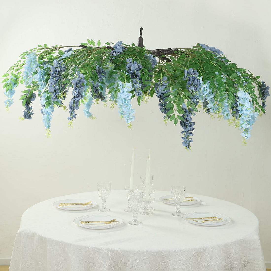 Artificial floral chandelier with blue and green foliage above a dining table.