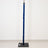 Blue padded vertical pole on a black base against a white wall