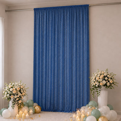 Blue pleated backdrop with floral arrangements, balloons, and candles at an event backdrop