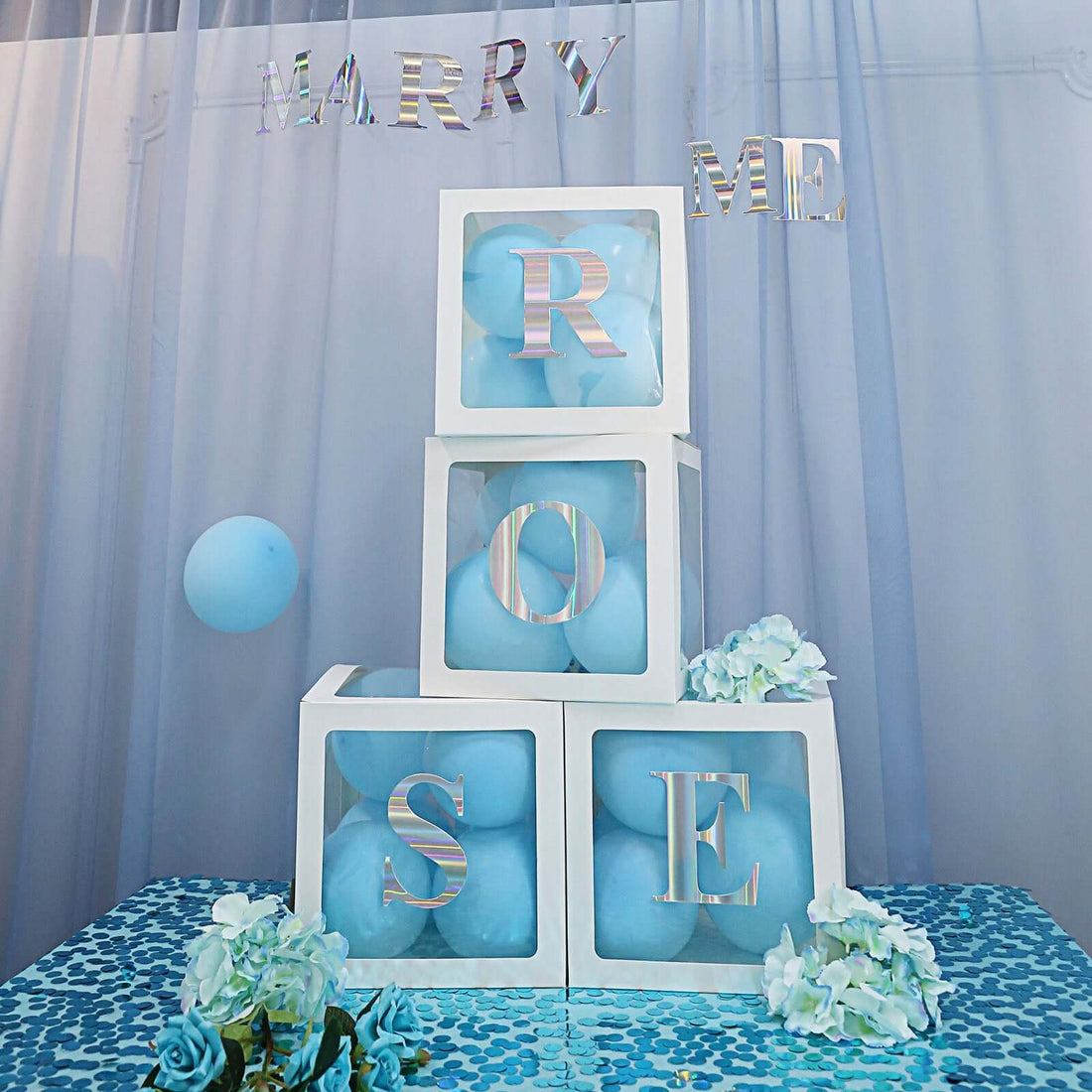 Decorative engagement display with blue balloons and flower accents.