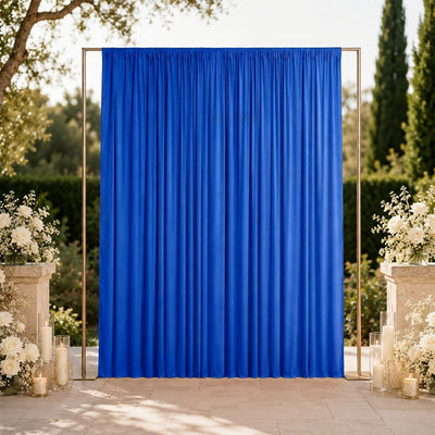 Blue wedding backdrop curtain with floral arrangements and candles outdoors