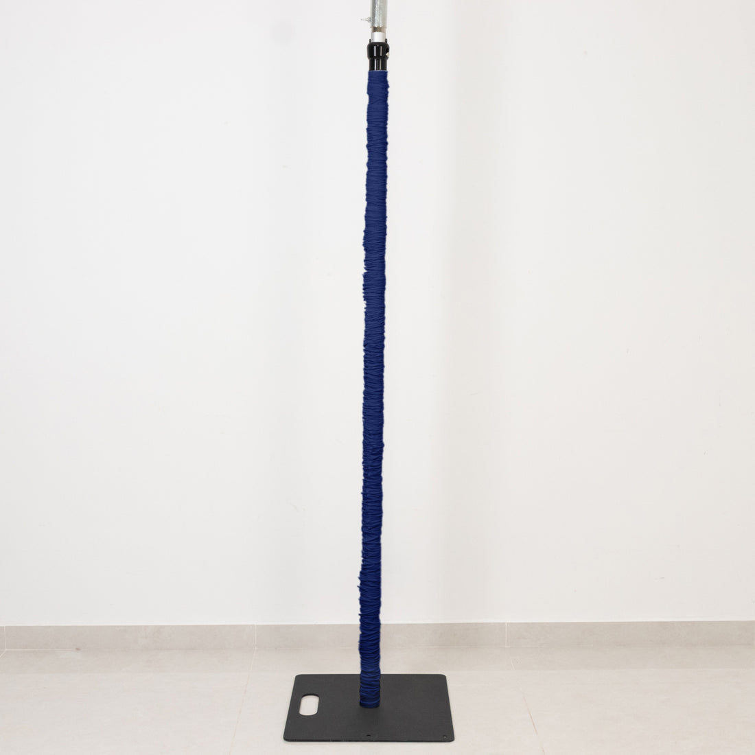 Blue wrapped pole on a black base against a white wall