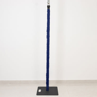Blue wrapped pole on a black base against a white wall