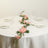 Floral table centerpiece with pink roses and greenery on a dining table.