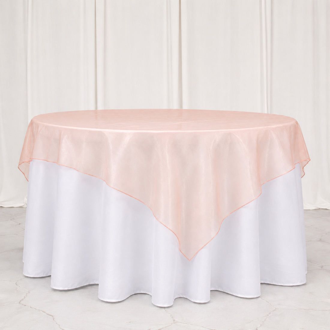 Blush pink round tablecloth overlay on white round table setting