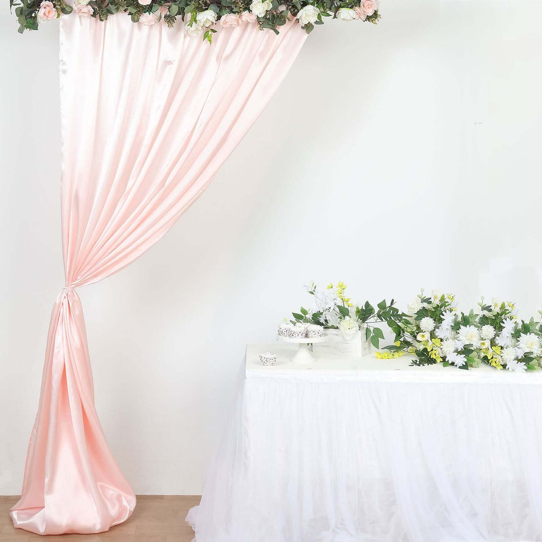 Blush pink draped curtain backdrop with floral garland and table