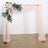 Floral wedding arch with draped fabric in soft pink tones.