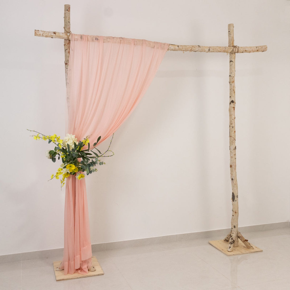 Wooden arch with pink drapery and floral arrangement