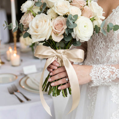 Bride holding ivory rose wedding bouquet with eucalyptus ribbon