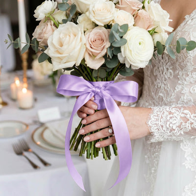 Bride holding white and blush rose bouquet with lavender ribbon