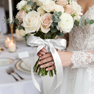 Bride holding white rose and eucalyptus wedding bouquet with satin ribbon