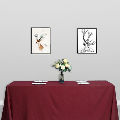 Framed deer art prints displayed above a burgundy table setting.