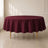 Burgundy round tablecloth on a table in a bright, elegant setting.