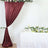 Maroon satin curtain draped elegantly with floral arrangements on a table.