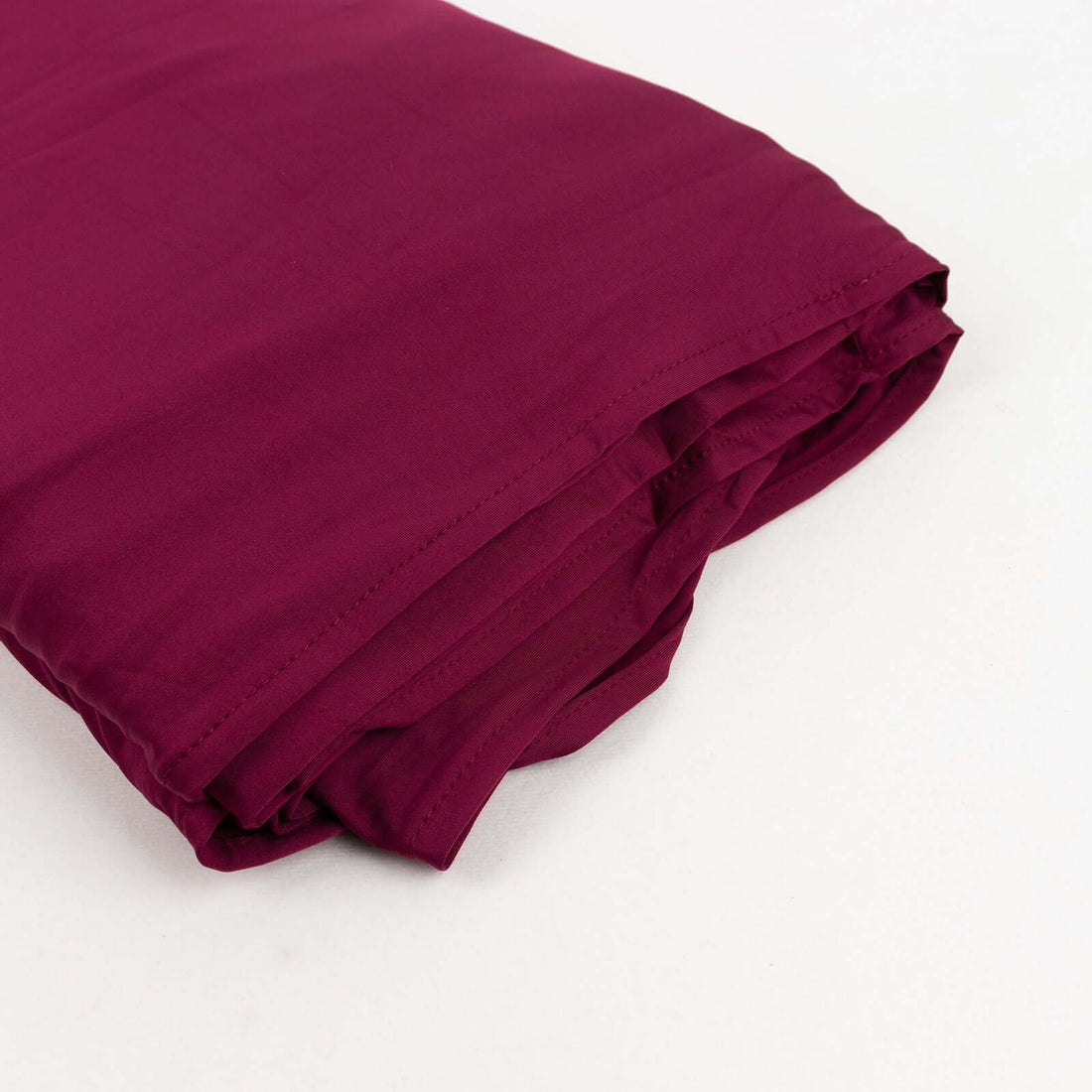 Burgundy fabric roll on white backdrop