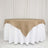 Round table with a beige burlap tablecloth over a white table skirt.