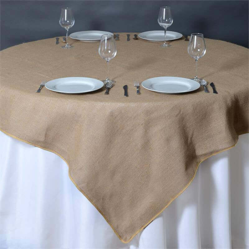 Burlap tablecloth on a round table set for dining with plates and glasses.